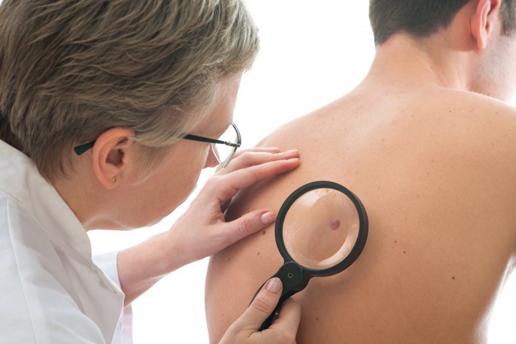 doctor inspecting patient for skin cancer