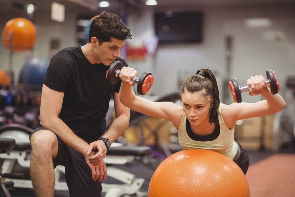 personal trainer and woman working out in the gym