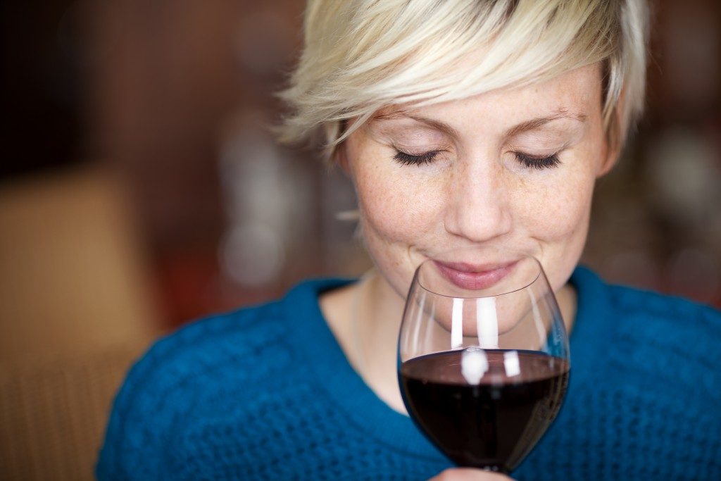 Closeup portrait of young female customer drinking red wine with eyes closed