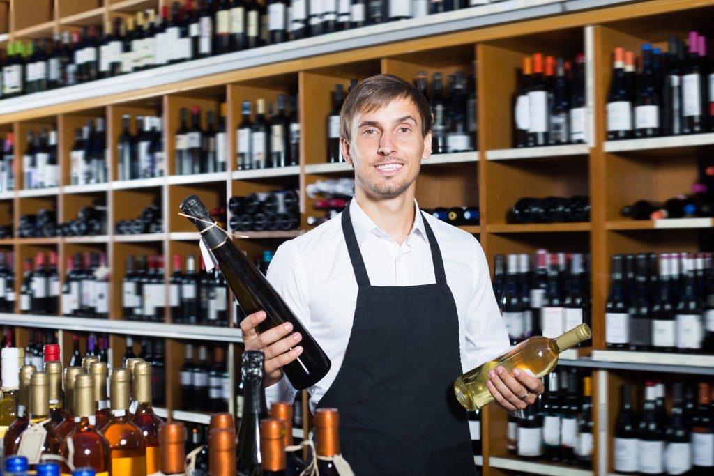 Man wearing apron selling wine