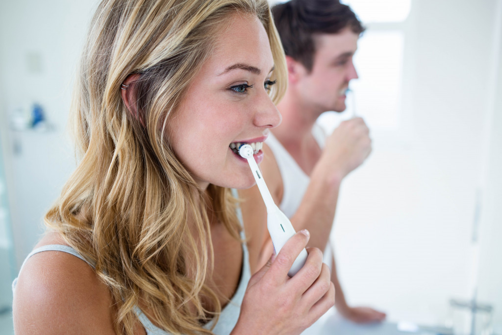 man and woman brushing their teeth together