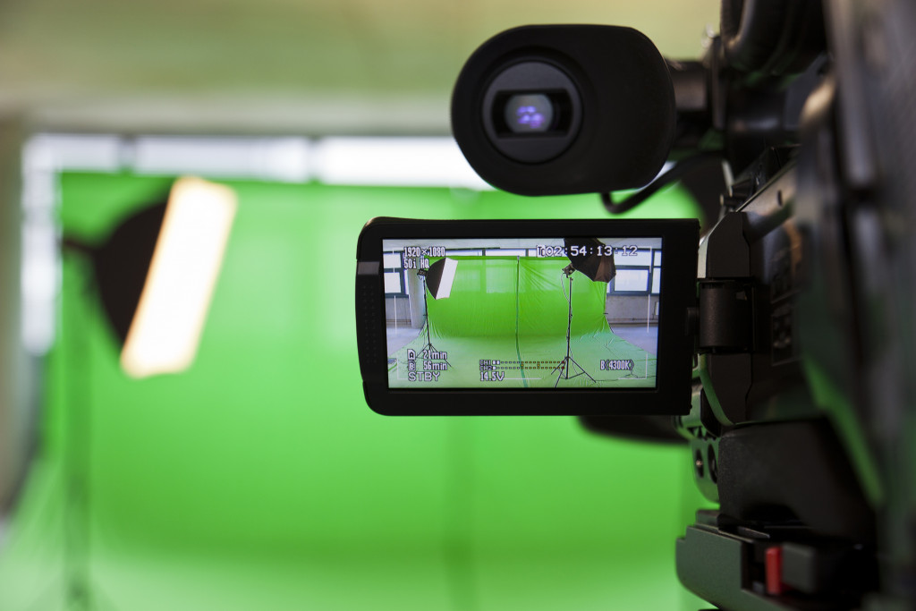 A professional camera filming a green screen set