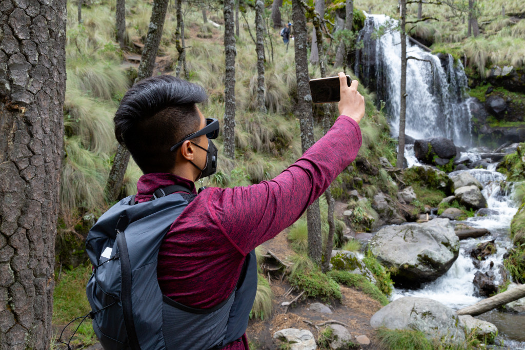 A man documenting his travel in a waterfall at a national park