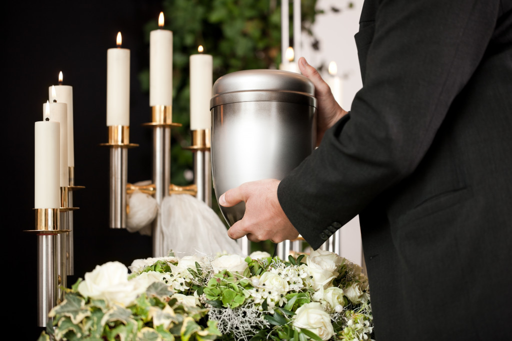 a Man holding a jar with remains of a pet on a funeral