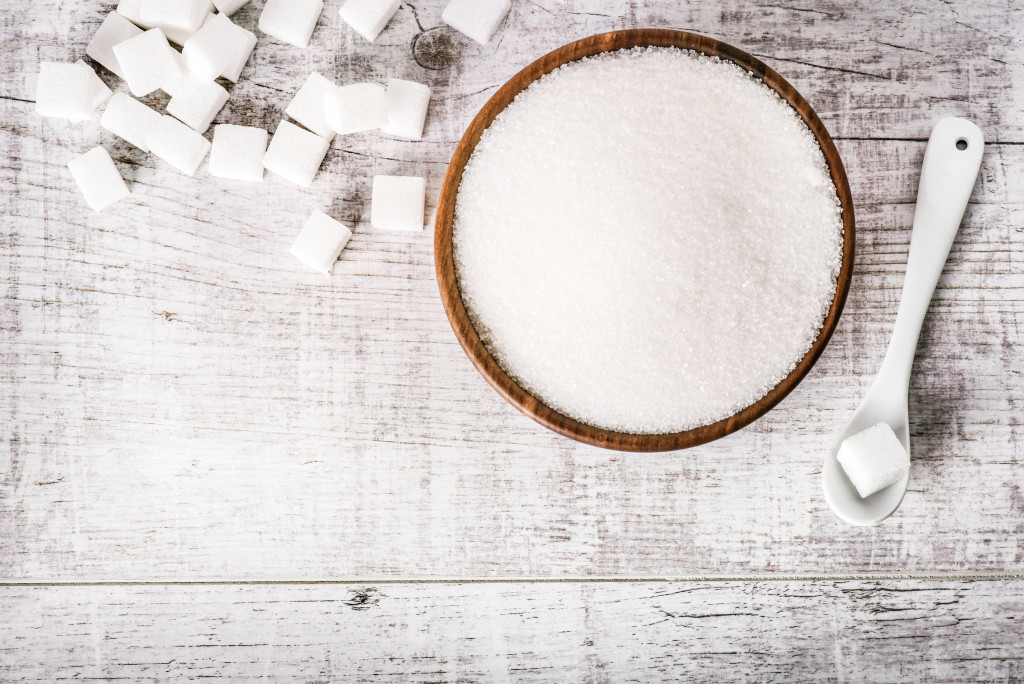 A bowl of sugar and some sugar cubes beside it