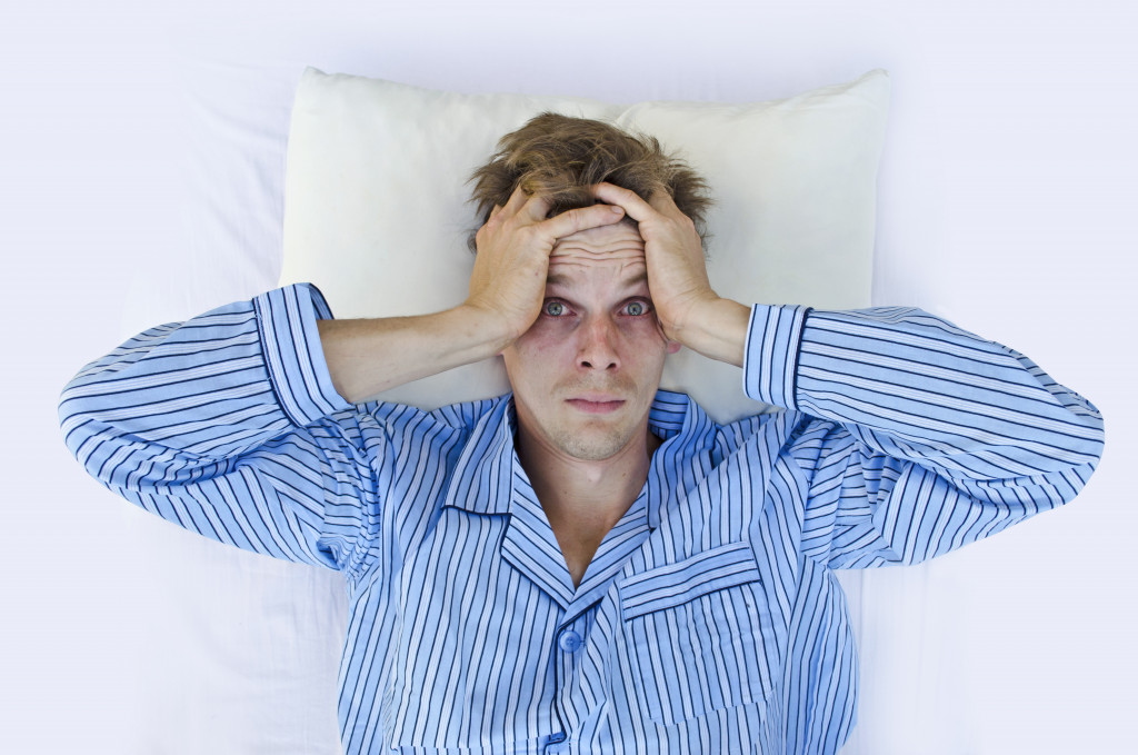 A man holding his head with bloodshot eyes after a restless night without sleep