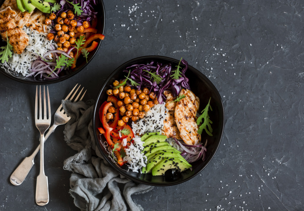 grilled chicken rice spicy chickpeas avocado cabbage pepper buddha bowl on dark background