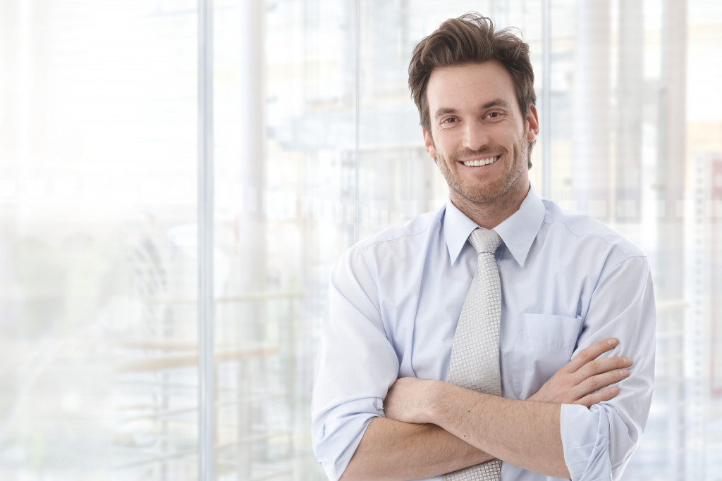 Smiling young man with his arms crossed in front of him.