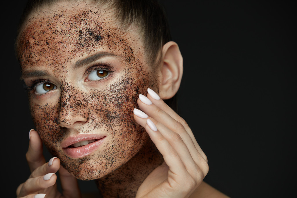 young woman with coffee scrub on face concept of exfoliation