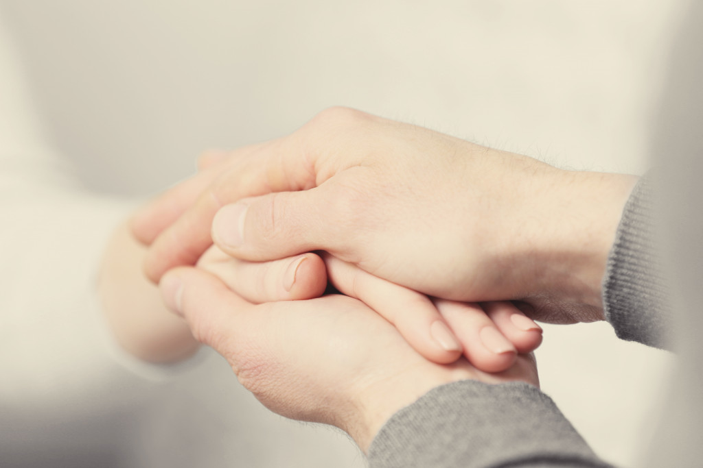 two people holding hands closeup