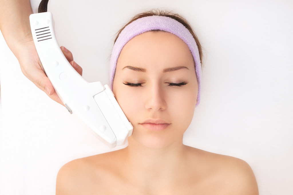 A woman getting a facial laser treatment in a spa