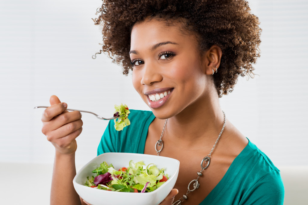 A woman eating a bowl of salad