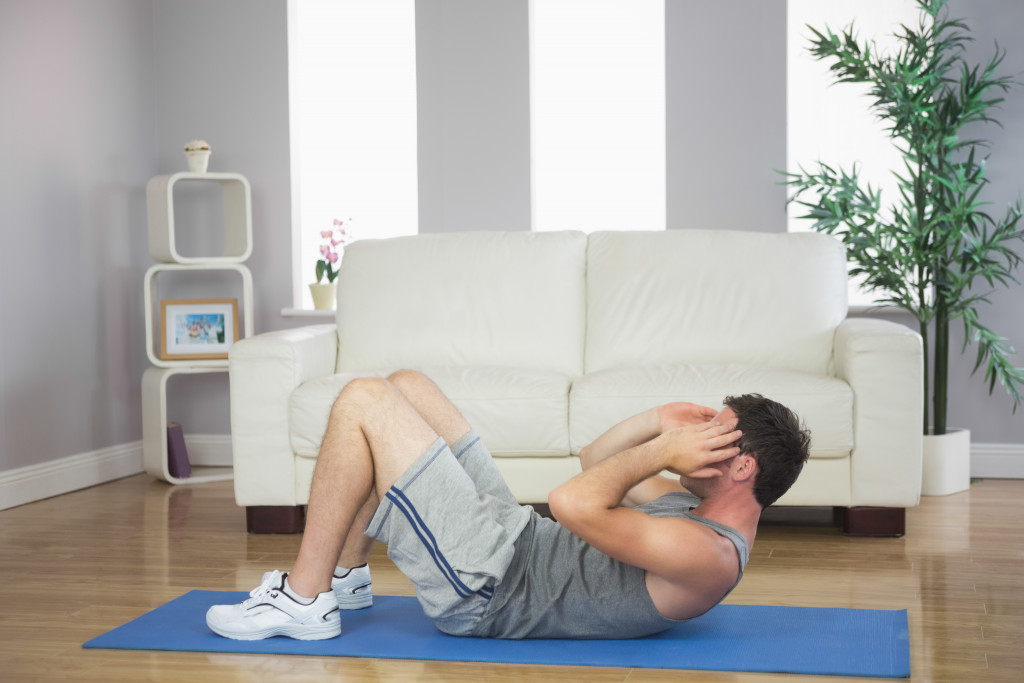 A fit man doing sit ups in the living room