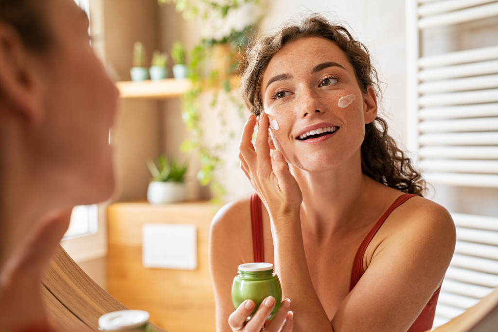 woman applying moisturizing cream on face