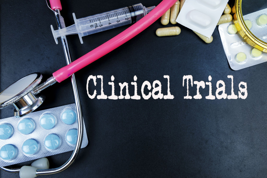 CLINICAL TRIALS words on black background with several medical tools and pills around